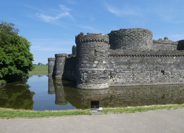 Beaumaris Castle reflected in its broad water-filled moat, the symmetrical curtain walls and round towers doubled in the still water.