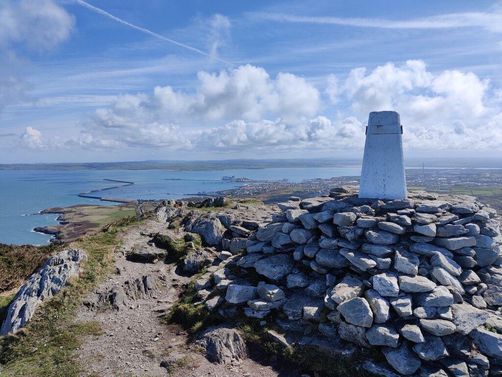 The trig point on the summit of Holyhead Mountain (Mynydd Twr) at 220 metres, the highest point on Holy Island, with open sky and the Irish Sea behind.