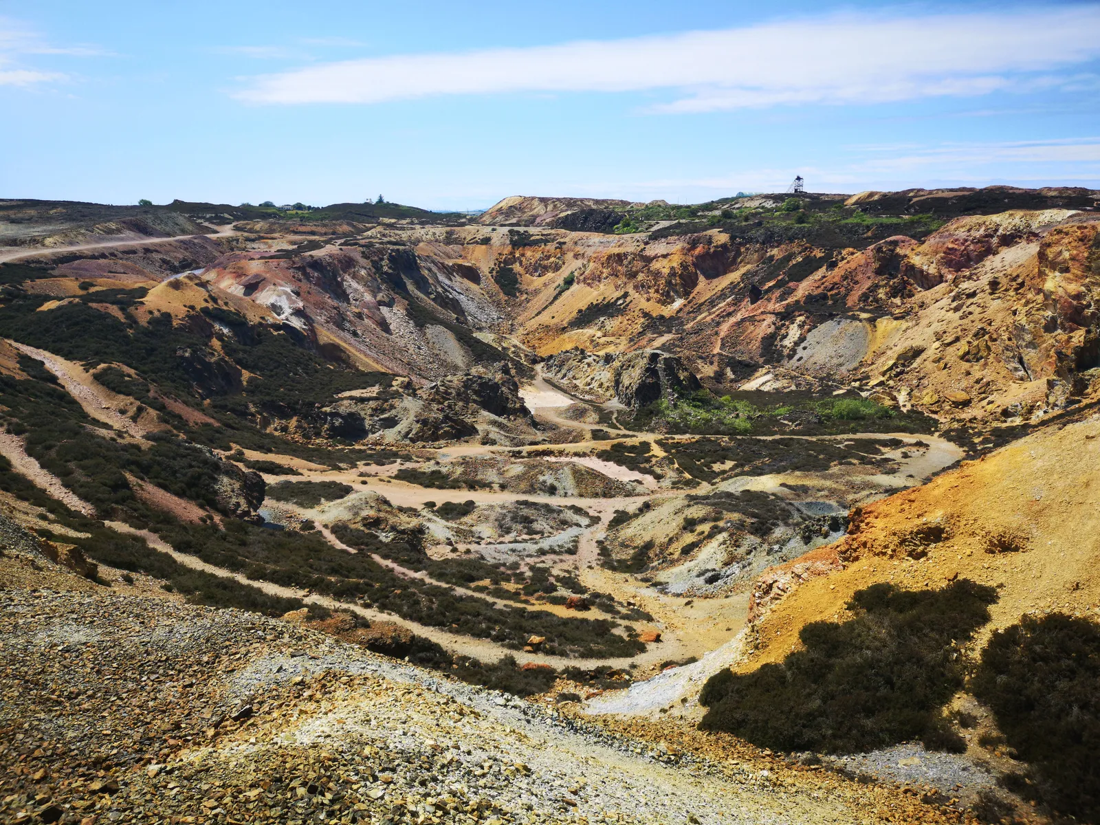 Aerial view of Parys Mountain near Amlwch, Anglesey — a copper-mined landscape of burnt orange, ochre and violet rock.